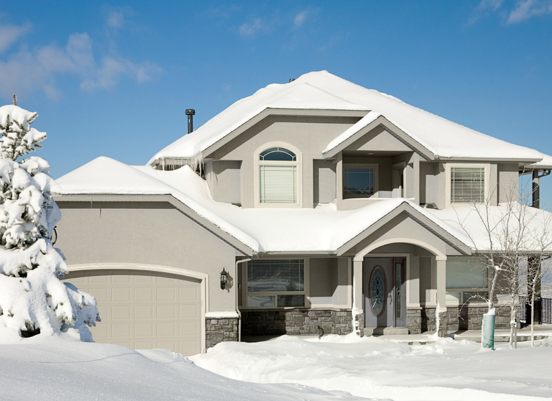 Beige house with stucco exterior with snowy background.