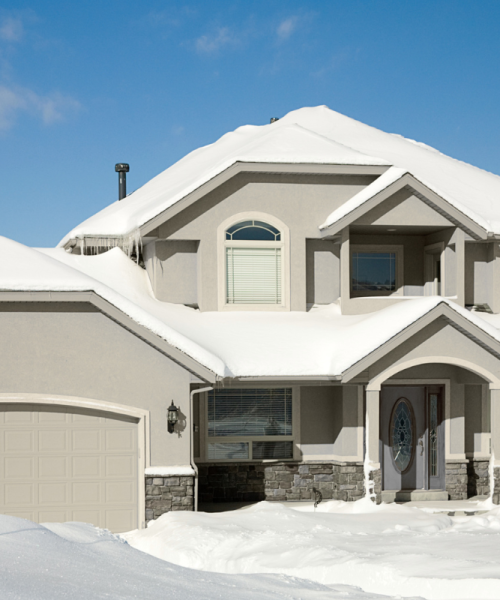 Beige house with stucco exterior with snowy background.
